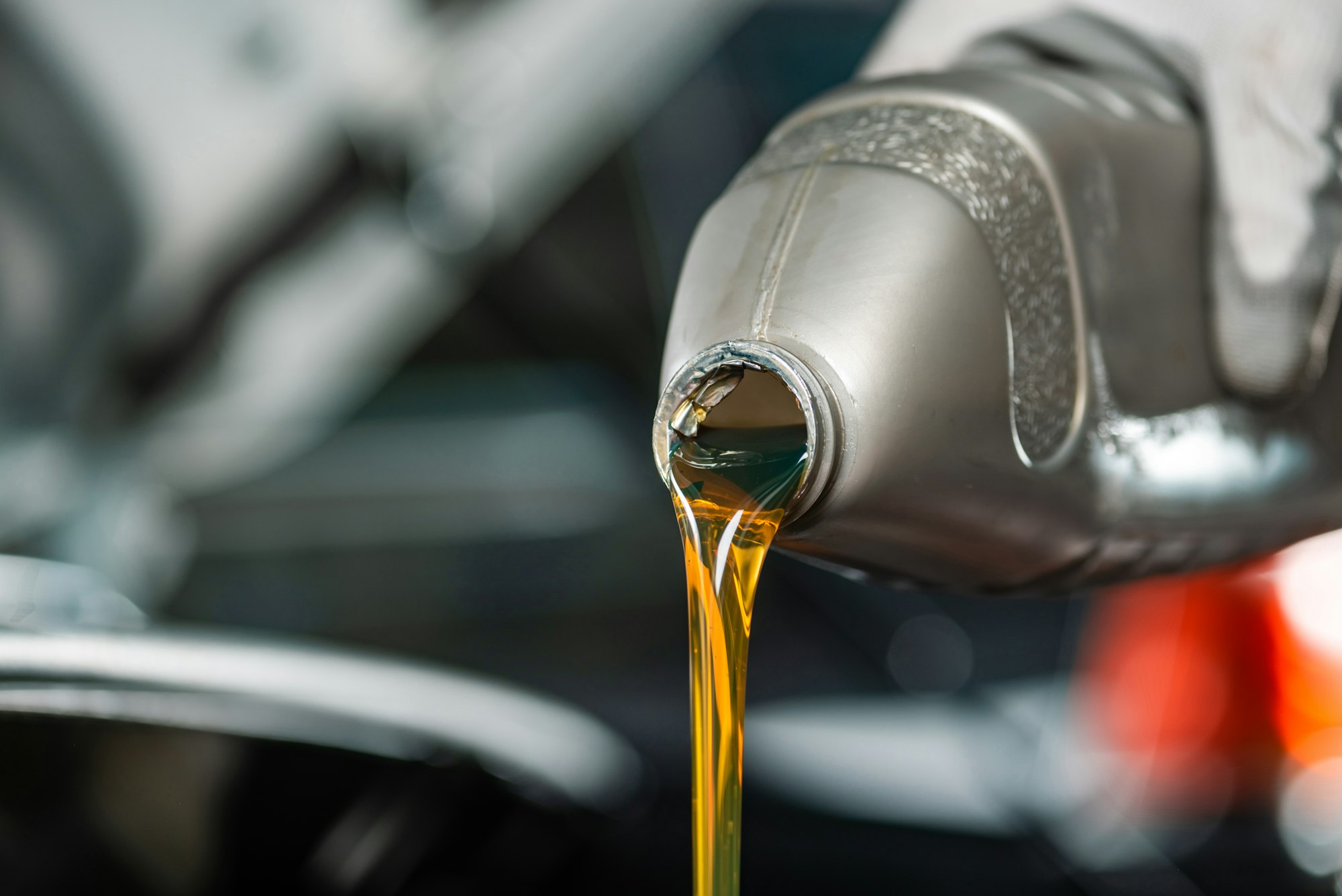 partial view of mechanic pouring motor oil from bottle